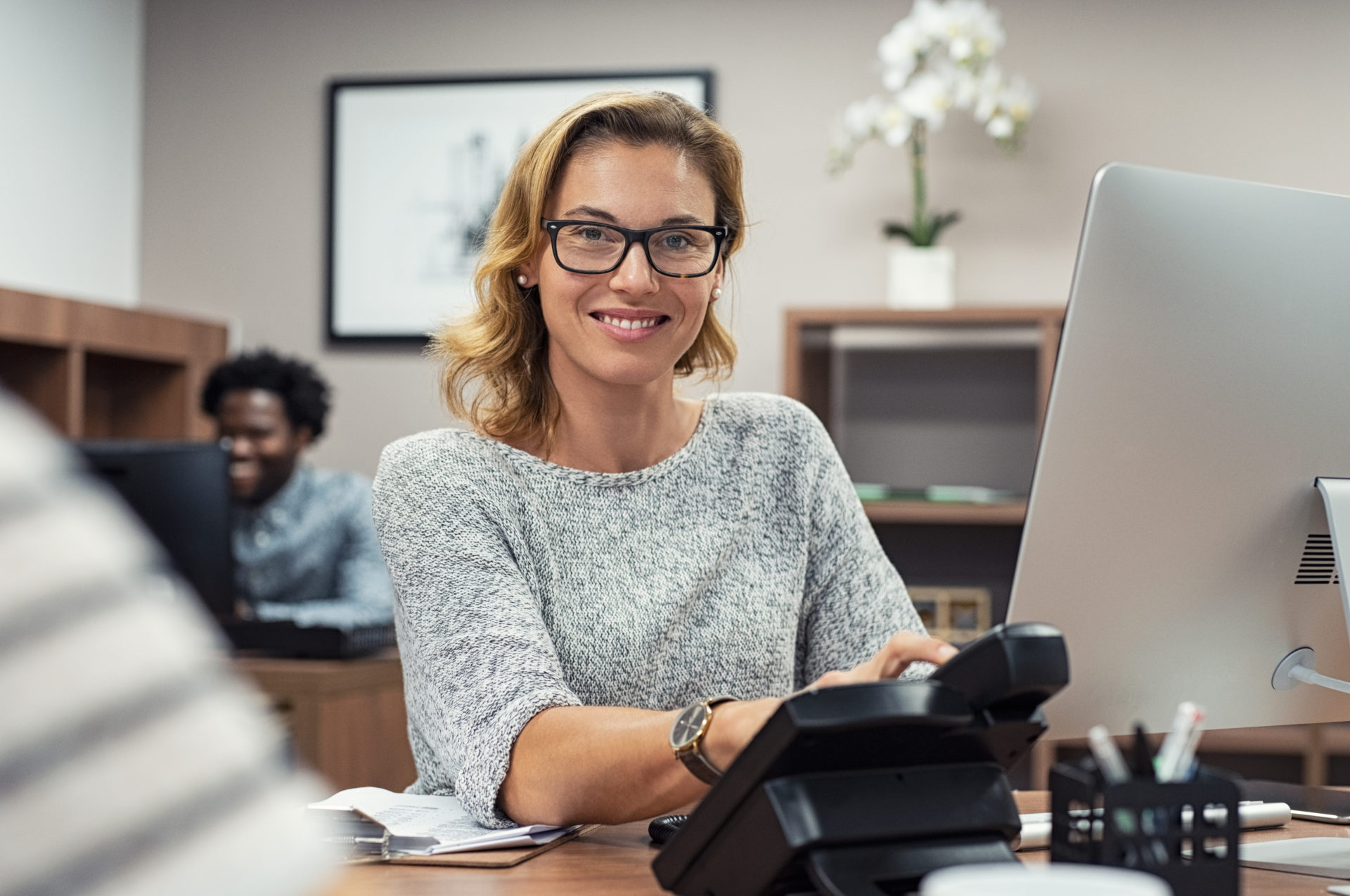 shutterstock_1281020668 Woman Smiling at Office Desk