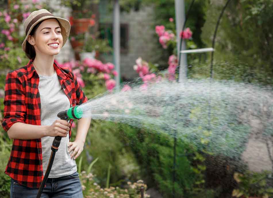 well_water_2 Woman using a garden hose to water plants